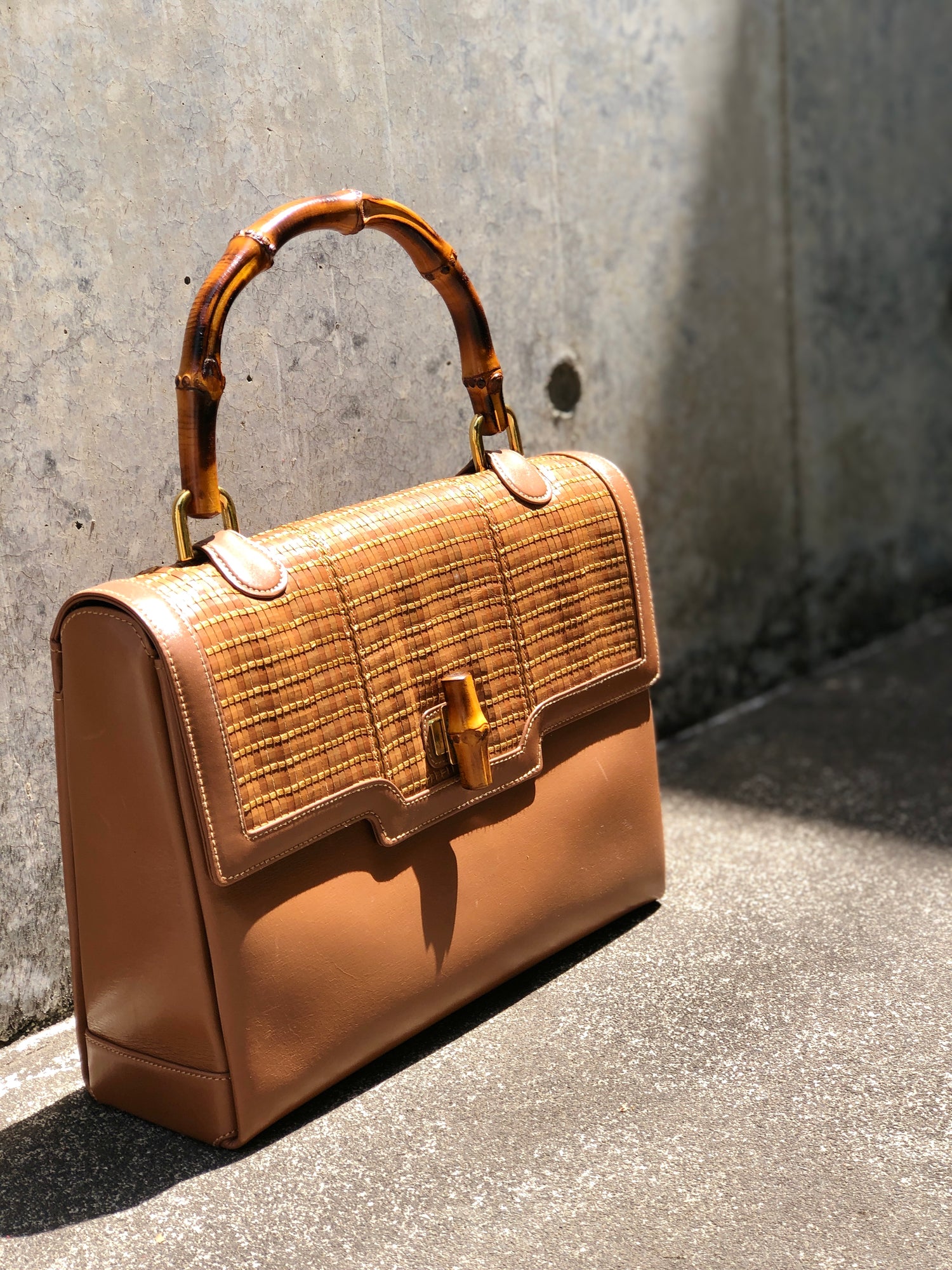 This is a chic brown Gucci handbag with a bamboo handle and woven texture, offering a timeless and elegant design.